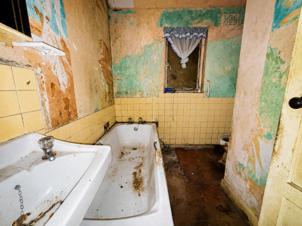 A damaged and dirty bathroom.