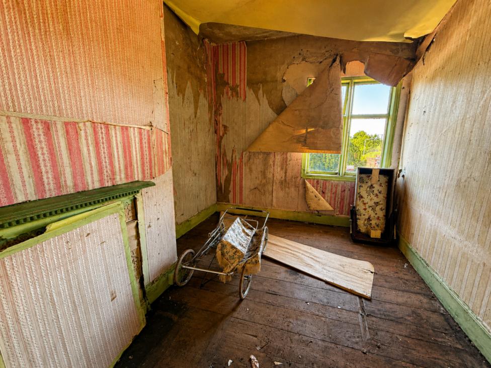 Inside one of the rooms which has been left in disrepair. The wallpaper has been ripped off.