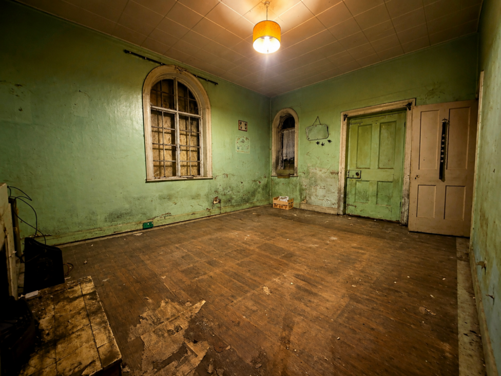 Inside another room which has been left in disrepair. The walls and floor are dirty.