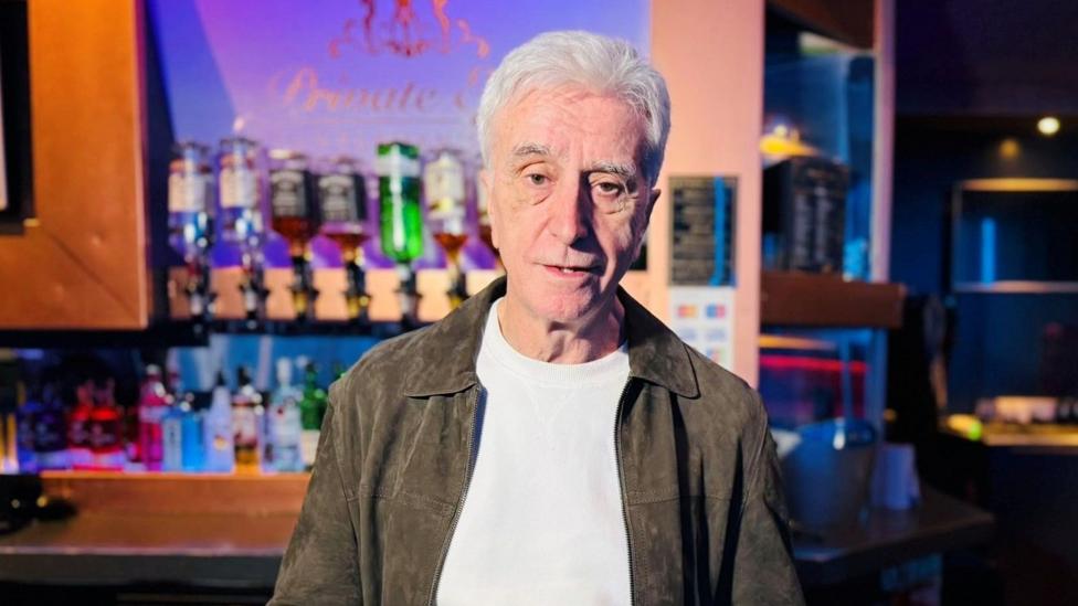 A man - strip club owner Tony Cochrane - in a strip club venue looking at the camera.