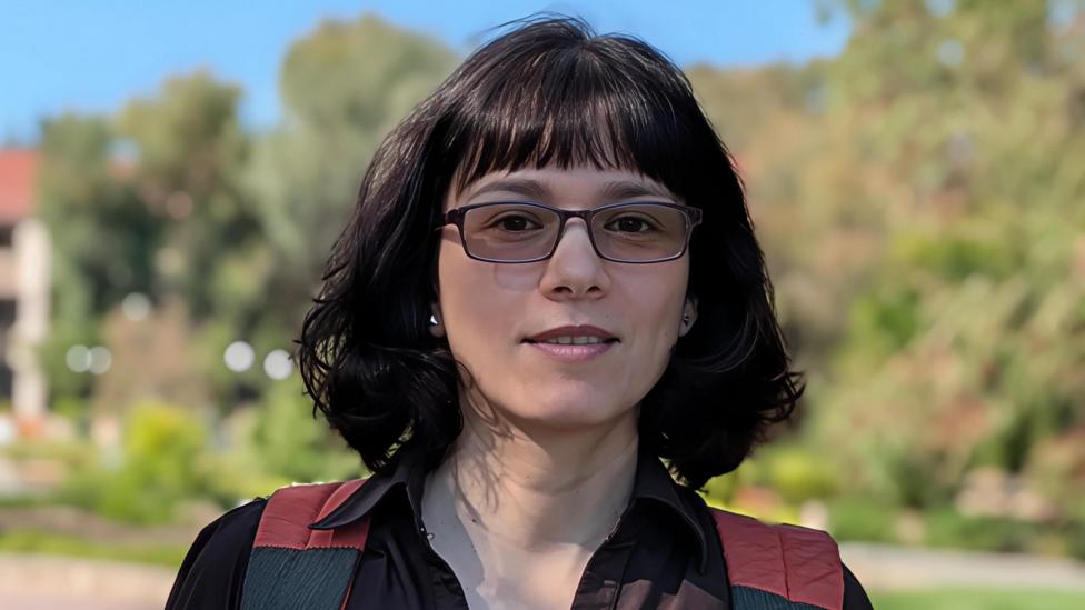 With dark short hair and wearing glasss Rika Antonova looks directly into the camera.