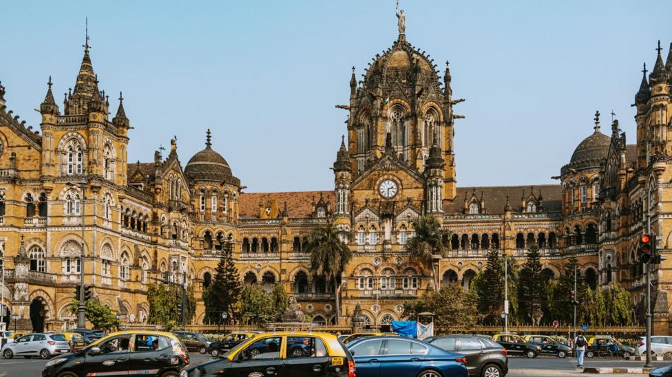 The Chhatrapati Shivaji Maharaj Terminus, a UNESCO World Heritage Site in Mumbai, features stunning Gothic architecture, surrounded by city life and vibrant traffic.