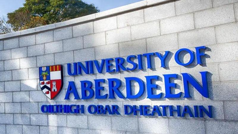 Bold blue lettering which says 'University of Aberdeen' on a grey brick wall.