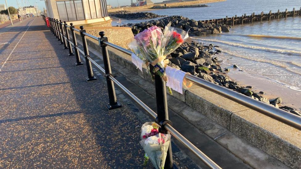 Flowers tied to railings at the scene