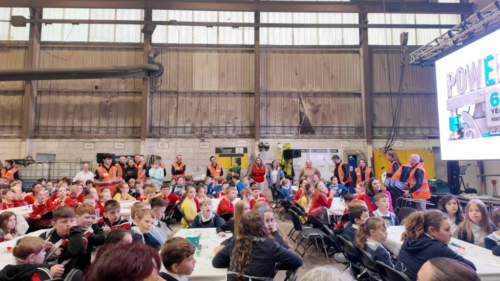 A large warehouse full of school children.