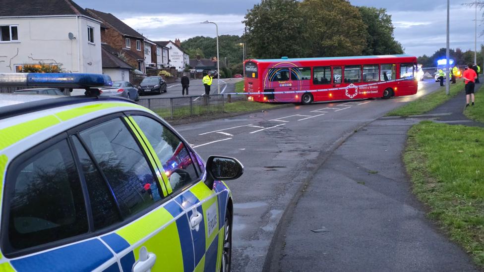 A bus reversed on to a kerb on a residential street with a police cordon in place