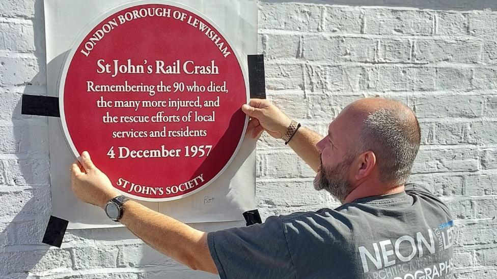 Plaque being placed on the wall at St John's station, remembering those who lost their lives