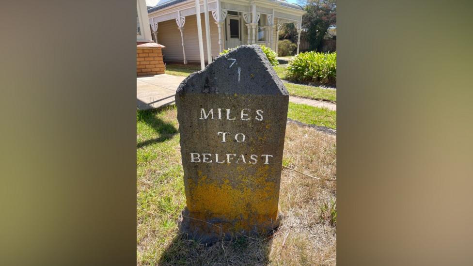 A stone sign in Port Fairy Australia says seven miles to Belfast