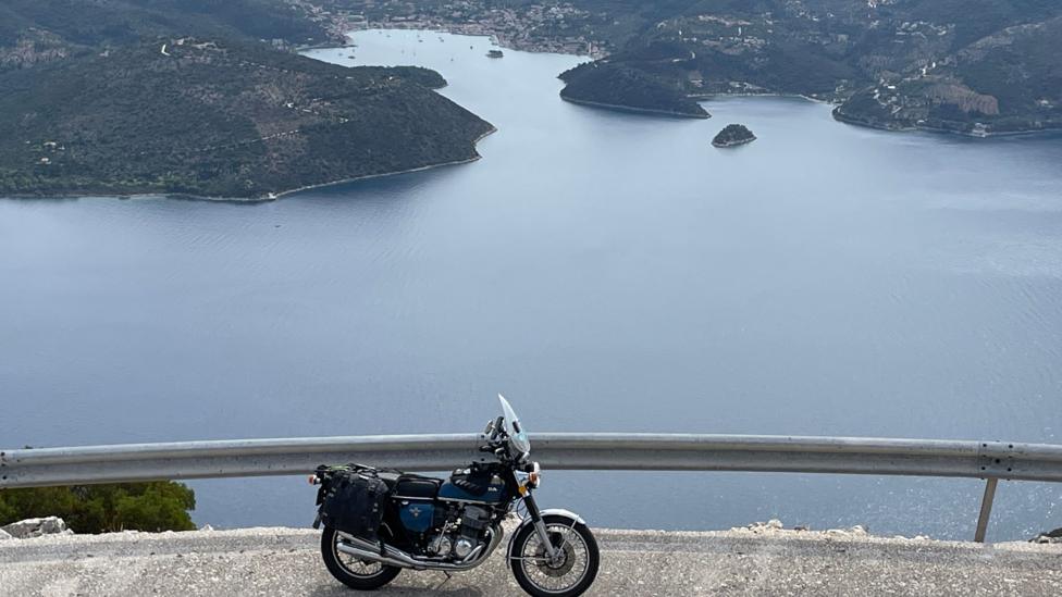 A motorbike is parked above a lake or inlet in Greece
