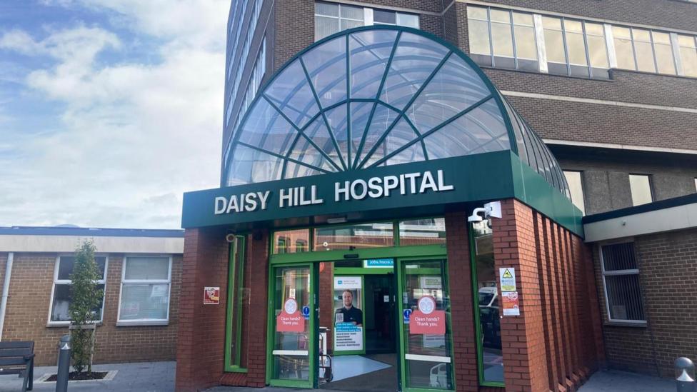 Red brick building exterior, it has a green steel and glass domed entranceway that says Daisy Hill Hospital