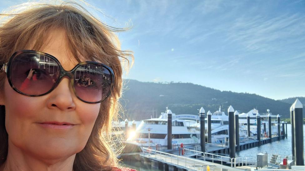 Karen Green wearing sunglasses as she stands in front of a harbour full of boats