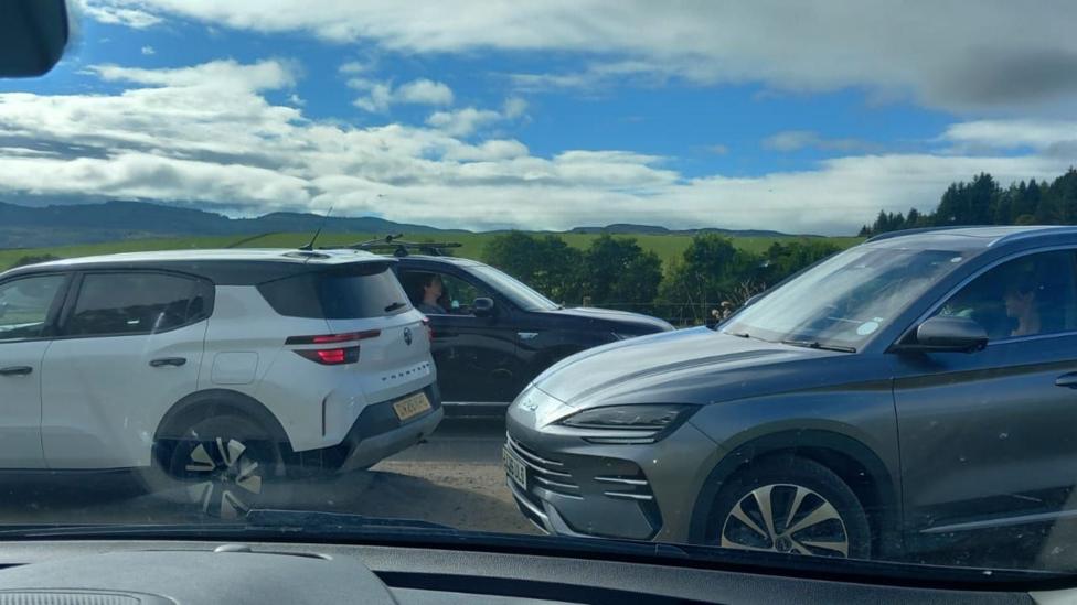 Three cars on the single-track road from the side.