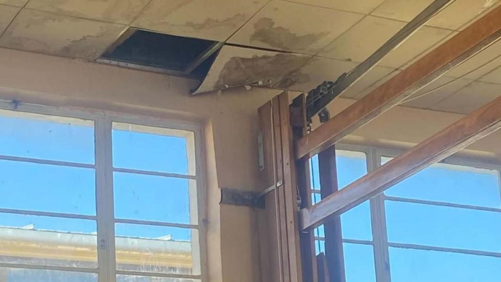 In an image provided by a parent, damaged ceiling tiles can be seen above a window and wall bars.
