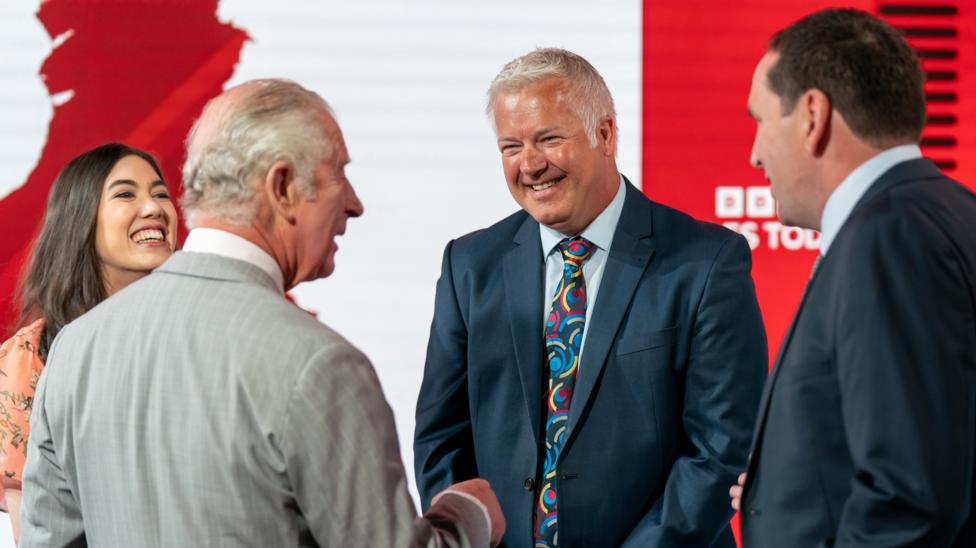 in 2022 Prince Charles is being introduced to BBC Cymru Wales weather presenters. Sabrina LEE and Derek BROCKWAY. The then Prince of Wales wears a grey suit while Derek is in a navy suit with a multi coloured tie. Him and Sabrina are pictured both smiling.