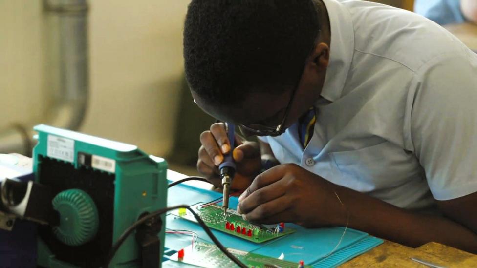 A secondary school student solders a circuit board in a classroom