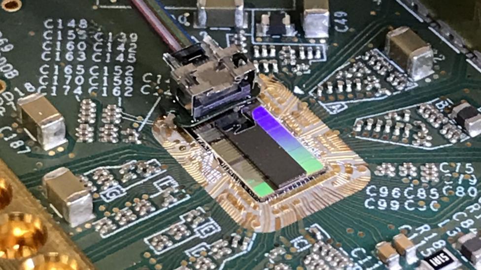 A circuit board featuring a optical fibre cable connected to an optical computer chip.