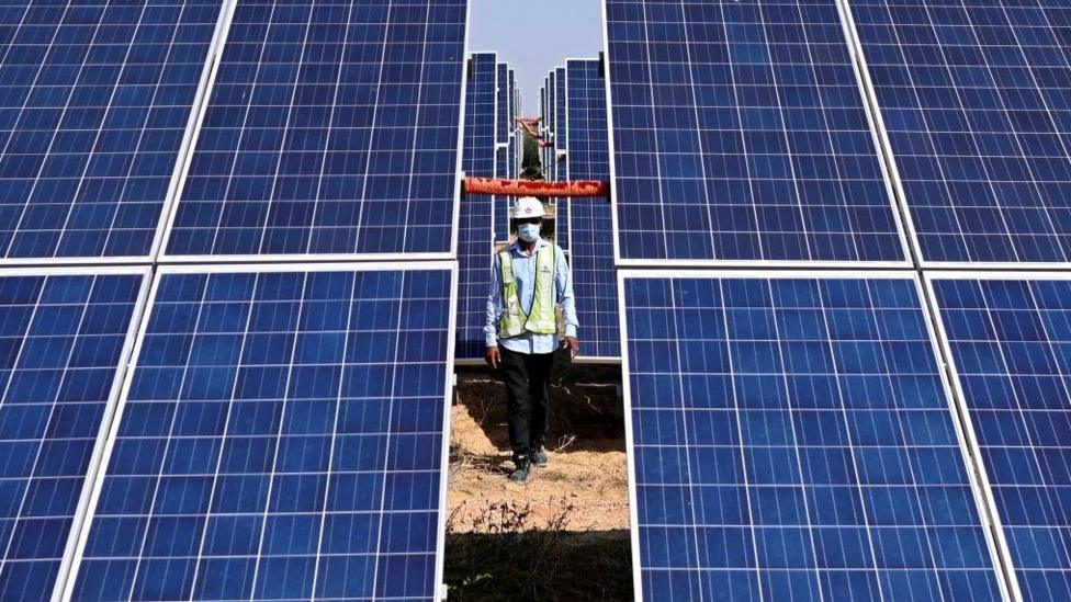 An engineer walks next to solar panels in the northern Indian state of Rajasthan
