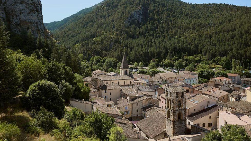 A view down a valley into a village in France nestled among trees