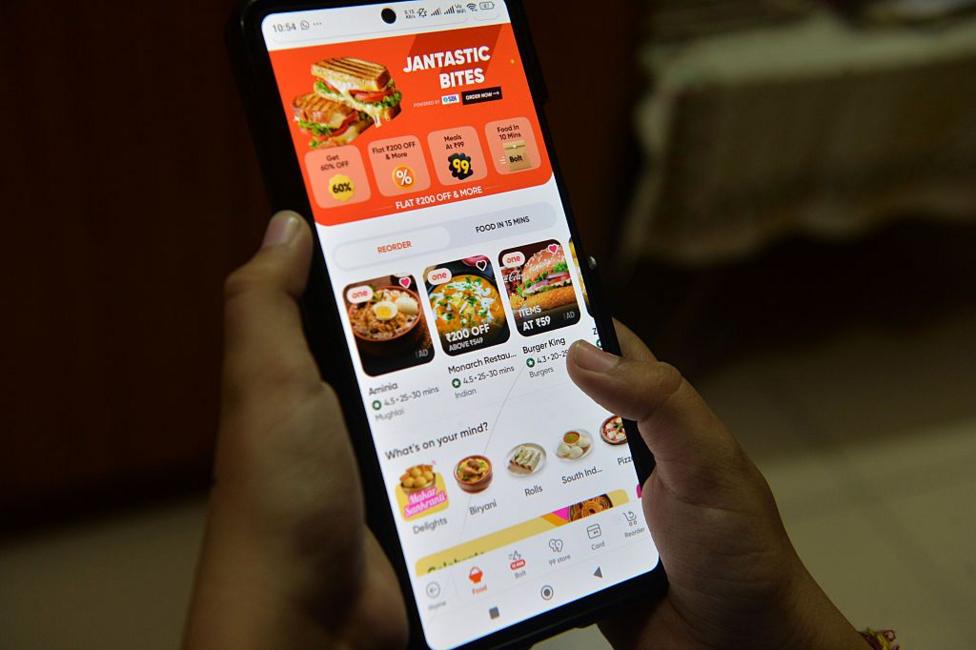 A boy uses a mobile phone to order food from the Swiggy Instamart delivery mobile application.