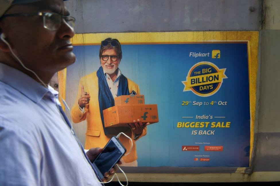 In this photograph taken on September 26, 2019, a commuter looks on as a train with advertisements of the upcoming festive sale of an online e-commerce portal featuring Bollywood actor Amitabh Bachchan passes by in Mumbai. 