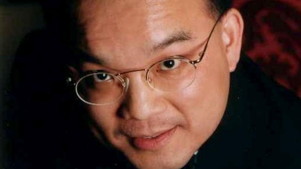 Close up image of Kenneth Law's face. He is looking at the camera and is wearing glasses.