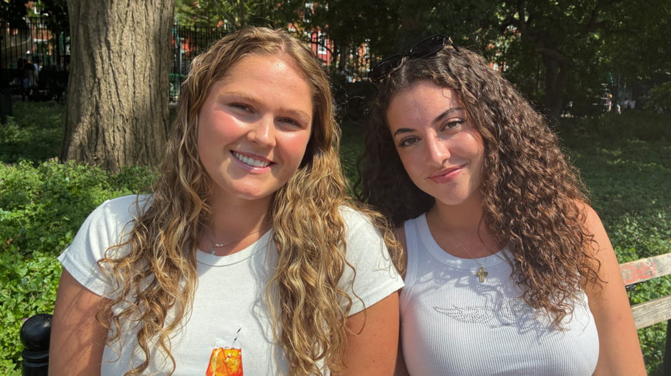 Two girls sitting on a bench smiling