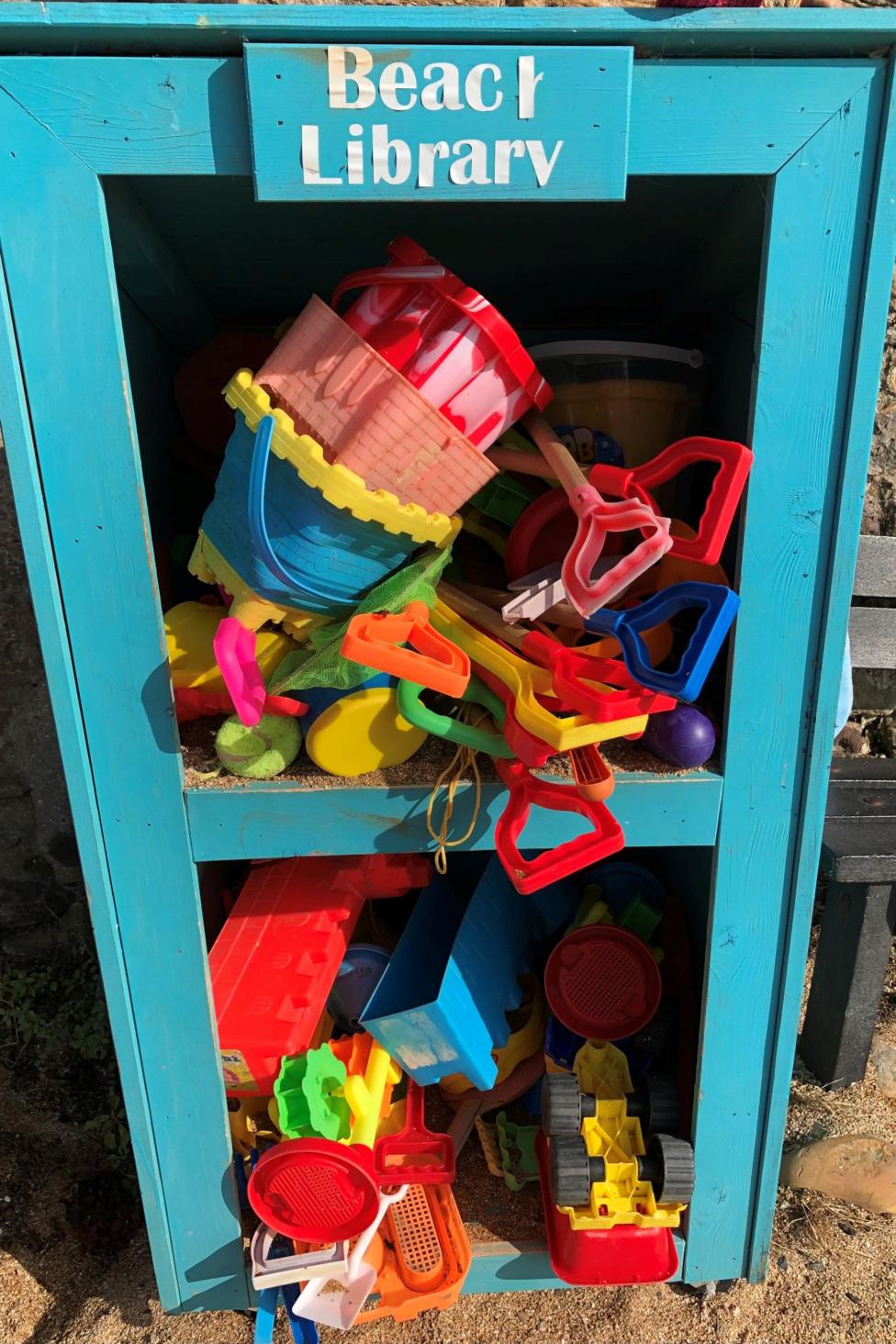 A bright turquoise “Beach Library” box is filled with colourful buckets, spades, toy trucks and sand-moulding tools for visitors to share. Set on a sandy shoreline, the community toy station offers beachgoers easy access to play equipment for a day by the sea. 