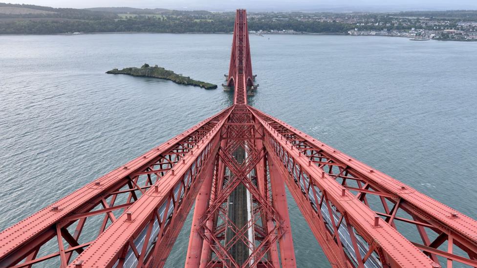 View along the red steel structure of the Forth Bridge stretching across the Firth of Forth.