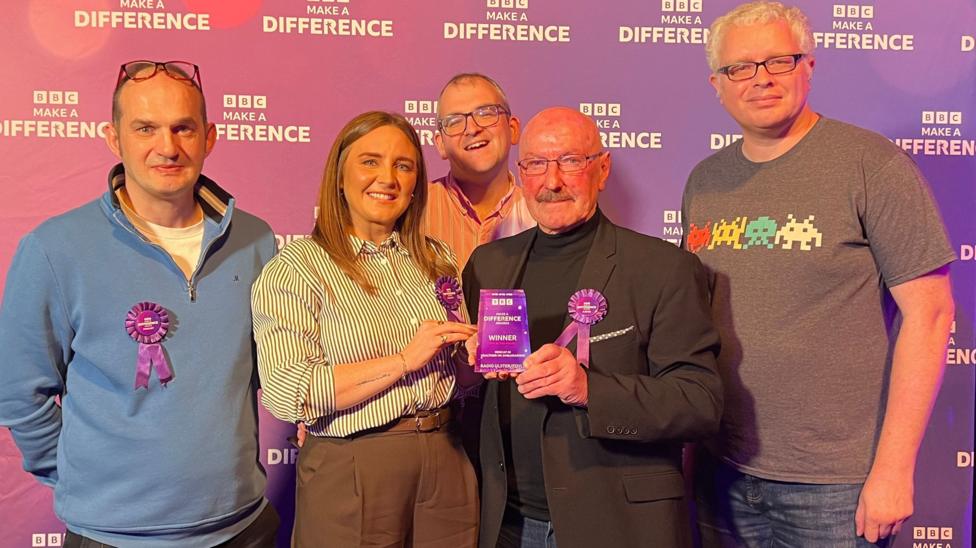 A group of people stand with an award