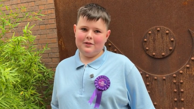 A boy with dark hair wearing a blue polo
