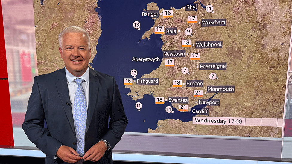 Derek stands in front of a weather map in the BBC Wales studio