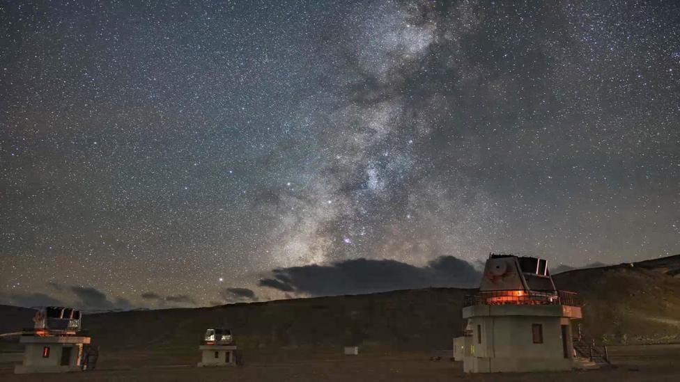 Telescopes standing in between hills with the milky way visible in Hanle, Ladakh
