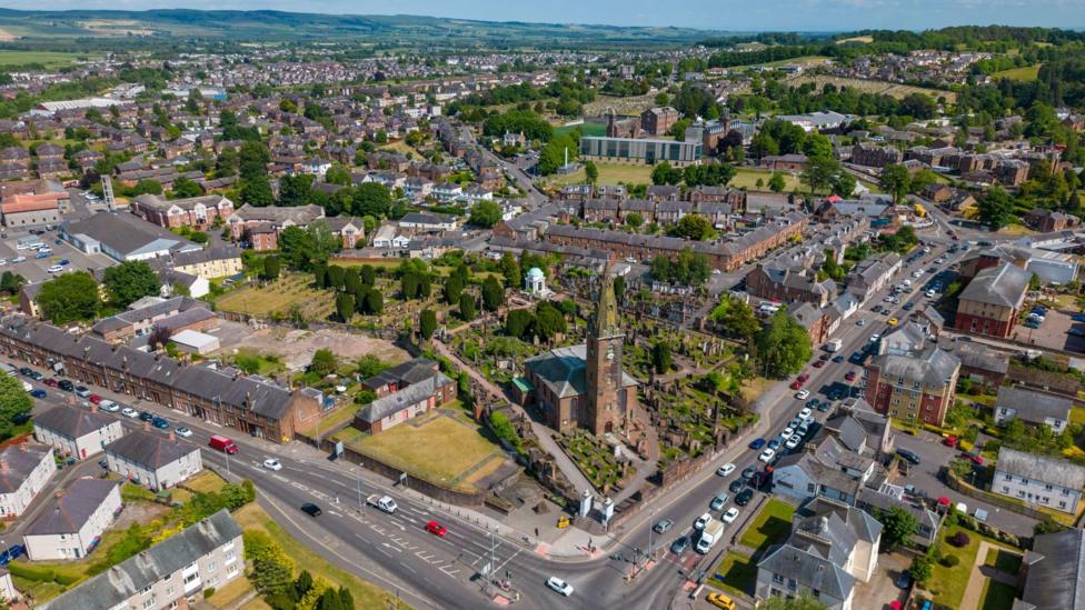 An aerial view of the town of Dumfries with a large sandstone tower in the foreground and buildings spread out behind it