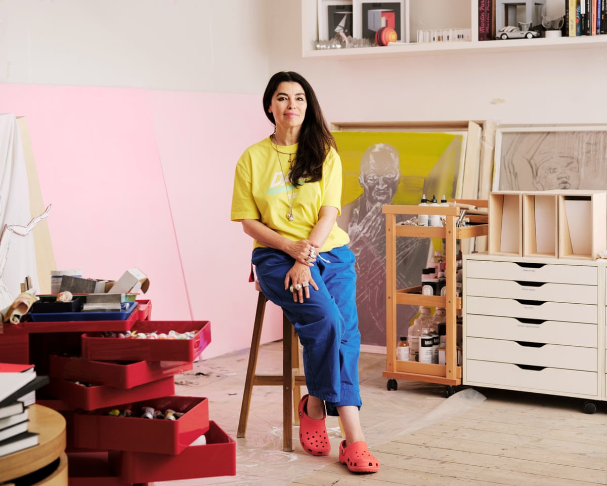 Photo: theukpulse.co.uk Es Devlin in a yellow T-shirt and blue trousers standing in her studio