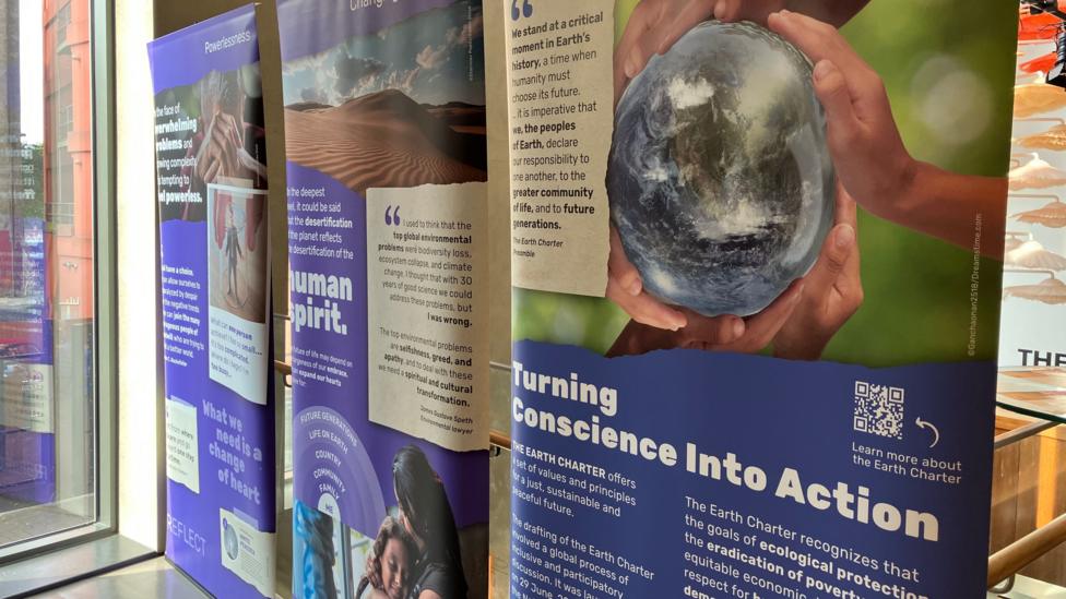 Three pop-up banners with an image of a globe with hands around it and the words "turning conscience into action" visible.