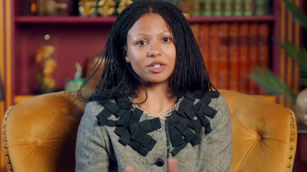 Myha'la in a smart grey and black suit