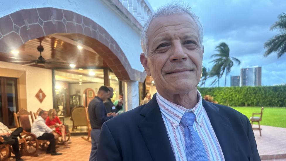Hugo Orizondo smile at the camera, standing in front of other guests at the event in Miami