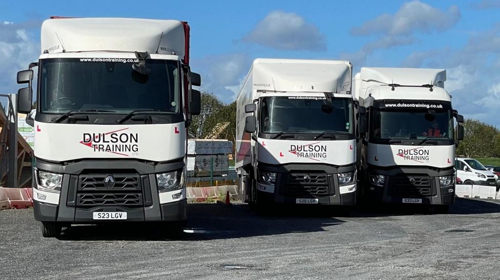 This image shows the front of three white lorries lined up next to each other. "Dulson Training" livery can be seen below the windscreen.