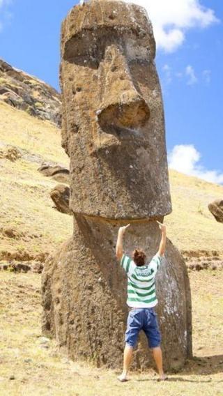 A man stands wearing the Wright top in front of one of the famous stone heads at Easter Island.