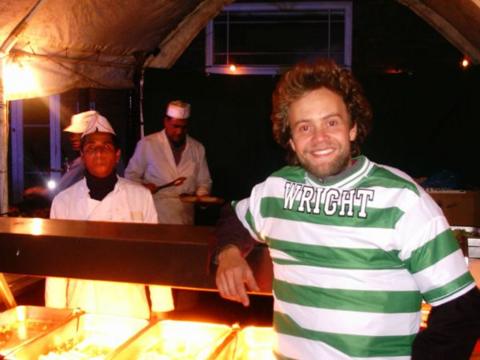 A man wearing the strip back-to-front, sits in front of a busy restaurant kitchen in Turkey.