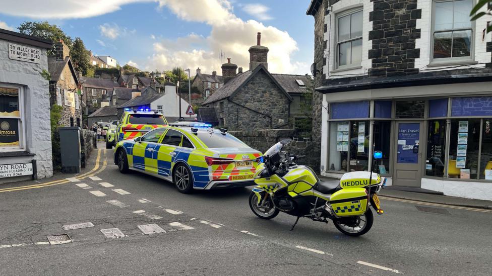 Police vehicles on a high-street road in a town