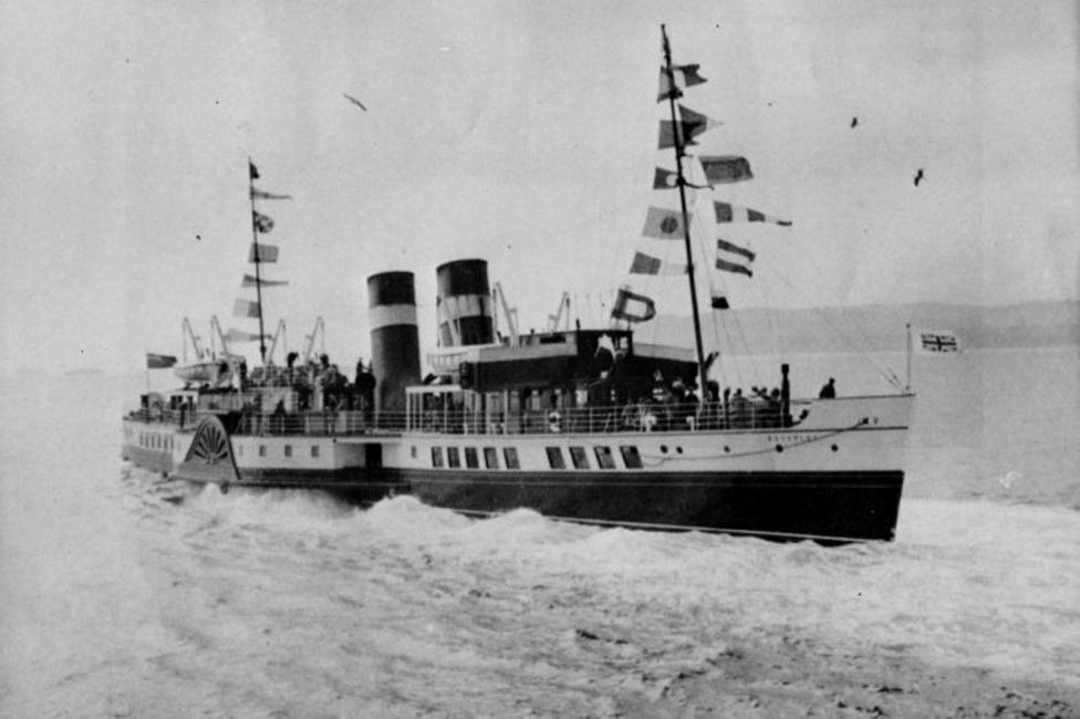 An old black and white image of the Waverley paddle steamer on her maiden voyage in 1947, with flags displayed and lots of people on the outside decks.