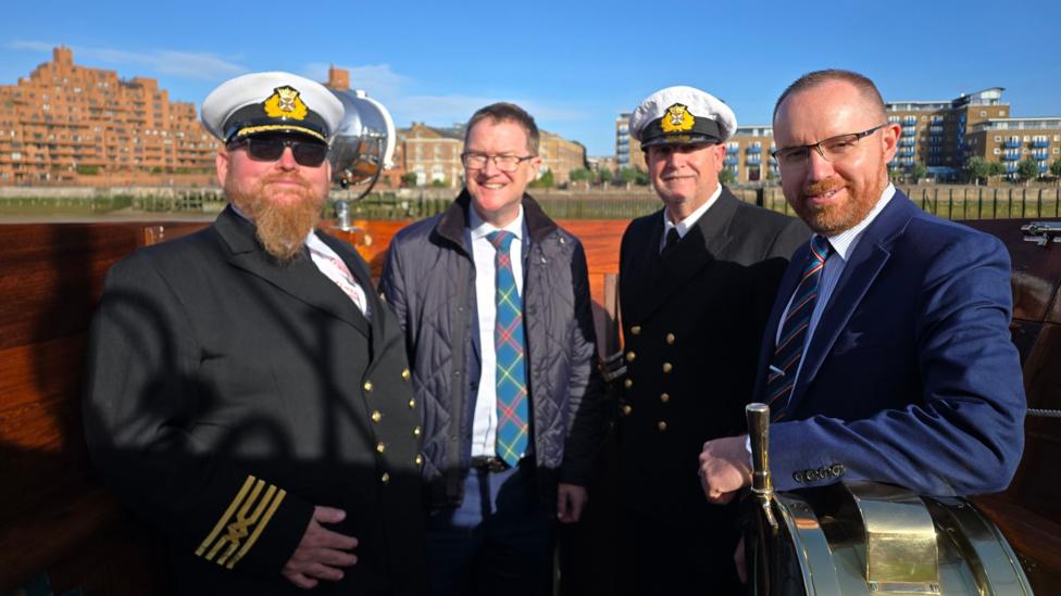 Waverley master Bruce Clark, LNER managing director David Horne, chief officer Gary Stevenson and general manager Paul Semple standing on the deck of the paddle steamer Waverley, with two in maritime uniforms. The River Thames waterfront is visible in the background.