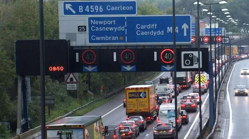 A wide shot of the M4 in Newport, showing a large number of cars queuing along the three-lane road.