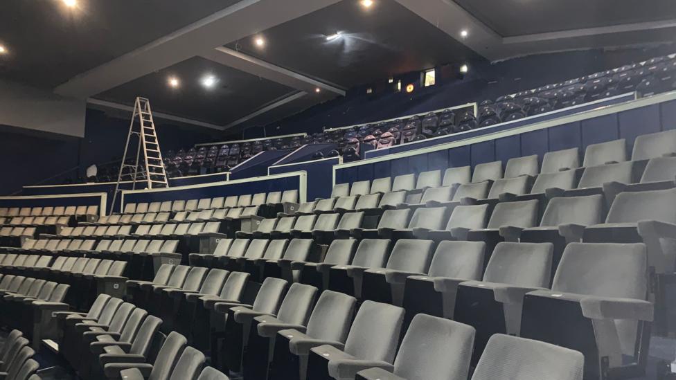 Rows and rows of cinema seats with a ladder in the background