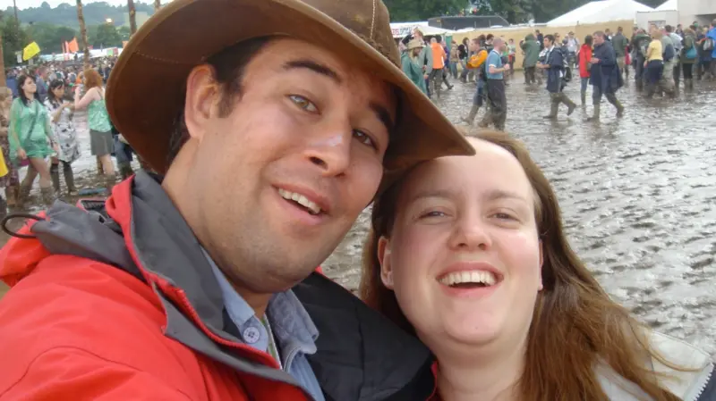 A man and a woman smiling in a muddy field