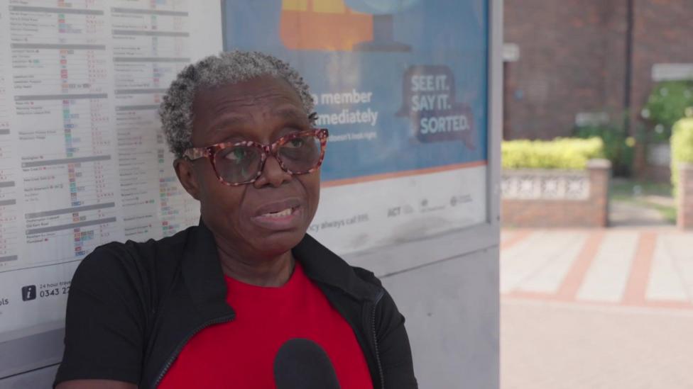 A woman at a bus stop in Greenwich.