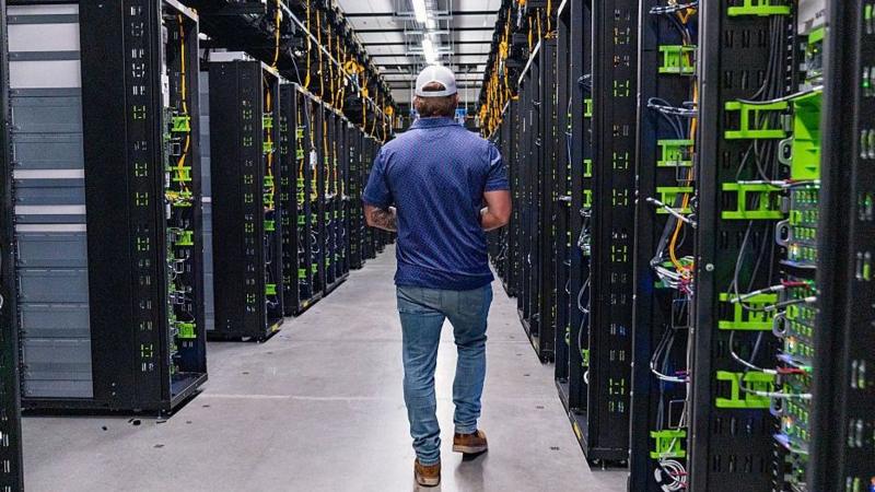 A man walking isnide a data centre, with rows of servers.