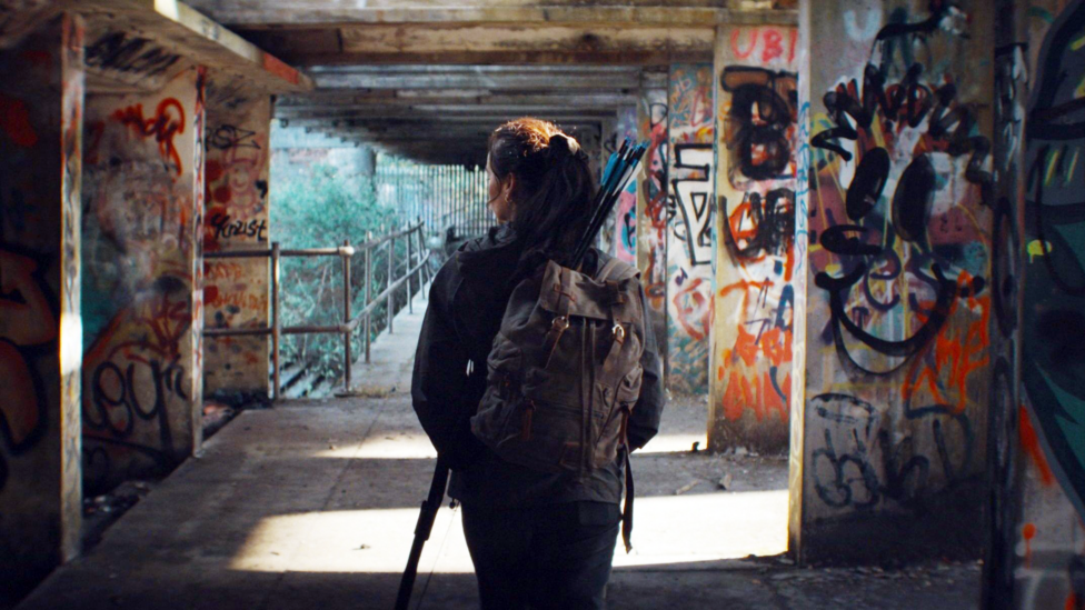 Jade McDonald walks through a walkway with walls covered in graffiti.