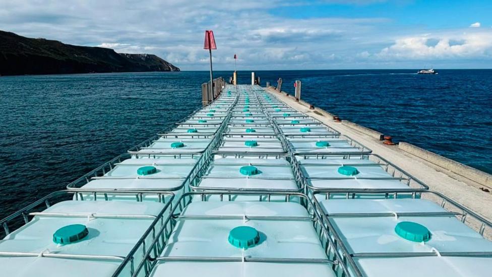 An image of a ship filled with large crates of water.